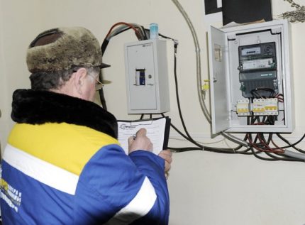 Представителят на енергоснабдителната компания снема показанията на електромера Специалистът снема показанията на електромера