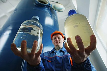 Реагенти за пречистване на вода Мъж държи в ръцете си бутилки с реагенти